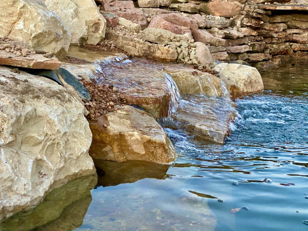 Small waterfall in backyard swim pond.